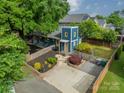 Overhead view of a blue two-story home featuring a yellow door, well landscaped yard, and a gravel parking area at 2915 Wesley Ave, Charlotte, NC 28205