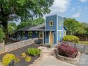 Two story home featuring a yellow door, beautiful landscaping and a lush green tree canopy on a partly cloudy day at 2915 Wesley Ave, Charlotte, NC 28205