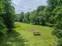 Expansive backyard area featuring a lush green field, mature trees, and a picnic table at 3387 Passmore Rd, Rock Hill, SC 29730