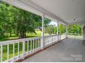 Covered front porch with white railing overlooks a large, well-manicured lawn at 40278 Nc 740 Hwy, New London, NC 28127