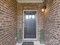 Inviting front entryway featuring brick facade, decorative shrubbery, and a charming 
