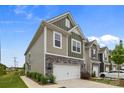 Stylish townhouse with a two-car garage and stone accents, showcasing modern curb appeal at 5207 Maynard Hill Dr, Monroe, NC 28110