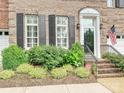 Close-up of brick front entrance, lush landscaping, and black shutters enhancing curb appeal at 6309 Wakehurst Rd, Charlotte, NC 28226