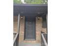 Home's gray front door, adorned with a classic knocker, is flanked by sconce lighting, enhancing curb appeal at 1002 Hemlock Dr, Shelby, NC 28150
