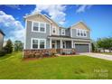 Two-story home with gray siding, stone accents, covered porch, and attached two-car garage at 1119 Bellshill Dv, Indian Trail, NC 28079