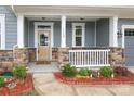Inviting covered front porch with stone pillars and a cozy seating area at 1119 Bellshill Dv, Indian Trail, NC 28079