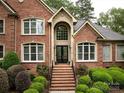 Elegant brick home facade highlighting arched entrance and meticulous landscaping at 1200 Firethorne Club Dr, Waxhaw, NC 28173