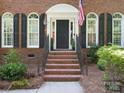 Elegant brick home entry featuring arched windows, black shutters, and a classic door with detailed trim at 12632 Landing Green Dr, Charlotte, NC 28277