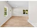 Bright living room with hardwood floors, a neutral color scheme, with ample natural light streaming through two windows and an exterior door at 1411 Duhart Ave, Gastonia, NC 28054