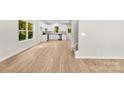 Bright, open living room showcasing hardwood floors, white cabinets, stairs, and ample sunlight filtering through large windows at 1411 Duhart Ave, Gastonia, NC 28054
