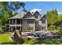Stunning backyard with an in-ground pool, stone fireplace, lush greenery, and a covered porch at 143 Jeremy Point Pl, Mooresville, NC 28117