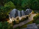 Expansive home with a gray roof, lush landscaping, and a long driveway, captured from an aerial perspective at 15038 Jockeys Ridge Dr, Charlotte, NC 28277