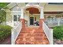 Inviting front entrance with brick steps, white railings, and a covered porch with decorative hanging flower baskets at 1701 Dearmon Dr, Charlotte, NC 28205