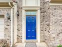 Close-up of the attractive blue front door of the home, accented by brick and elegant exterior lighting at 1769 Evergreen Dr, Charlotte, NC 28208