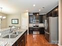 Modern kitchen featuring stainless steel appliances, dark cabinetry, granite countertops, and hardwood flooring at 1769 Evergreen Dr, Charlotte, NC 28208