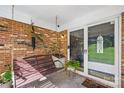 Cozy brick porch featuring a swing, brick wall, and tile flooring with a welcoming entrance at 245 Kingsway Cir, Charlotte, NC 28214