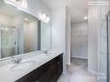 A modern bathroom is equipped with double sinks, white countertops, a large mirror, and a glass-enclosed shower at 2535 Ruby Dixon Crossing Dr # 19, Gastonia, NC 28056
