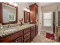 Bathroom with dual sinks, granite counters, dark wood cabinets, and walk-in shower at 7245 Willow Brook Ct, Denver, NC 28037