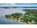 Stunning lakefront property surrounded by mature trees and lush landscaping with multiple docks at 8218 Bright Water Ln, Denver, NC 28037