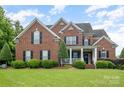 Charming two-story brick home with a well-manicured lawn and landscaping at 8962 Landsdowne Ave, Harrisburg, NC 28075