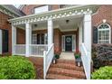 Inviting front porch with white columns, brick steps, and decorative flower pots at 8962 Landsdowne Ave, Harrisburg, NC 28075