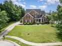 Beautiful brick home with manicured lawn, mature trees, and inviting curb appeal at 8962 Landsdowne Ave, Harrisburg, NC 28075
