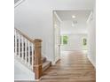 Bright hallway featuring wood-look floors, white trim, a staircase, and an open view into the living room at 9956 Manor Vista Trl, Kannapolis, NC 28027