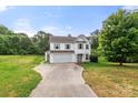 Two-story home with a two-car garage, neutral siding, and a long concrete driveway at 100 Brookstone Dr, Mount Holly, NC 28120
