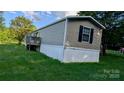 Single-story home with vinyl siding, a small deck, and a lush green lawn at 142 Sandra Dr, Statesville, NC 28625