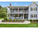 Inviting two-story home with a double porch and lush landscaping, enhancing its curb appeal at 16612 Grapperhall Dr, Huntersville, NC 28078