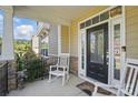 Inviting front porch with rocking chairs and a decorative front door with glass panels at 16831 Alydar Commons Ln, Charlotte, NC 28278