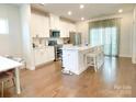Bright kitchen featuring stainless appliances, white cabinets, an island with seating, and wood floors at 2019 Tears Ln, Charlotte, NC 28217