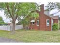 Exterior side view showcasing brick facade, white trim, and a well-manicured lawn with mature trees at 2036 1St Sw Ave, Hickory, NC 28602