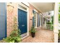 View of a blue front door with brick facade, lantern lighting and potted plants on a covered porch at 239 N Faulkner Way, Davidson, NC 28036