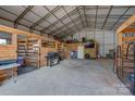 Spacious barn interior featuring wooden stalls, concrete floor, and ample storage space at 2676 Will Schronce Rd, Iron Station, NC 28080