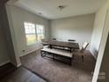 Bright dining room with a large window, carpet flooring and a long dark wood table with bench seating at 348 Ox Bow Cir, Mount Holly, NC 28120