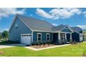 Lovely blue home featuring a garage, inviting covered front porch and manicured landscaping at 407 Bent Burr Crk, York, SC 29745