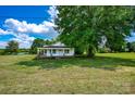 Single-story home with a covered porch and a red brick foundation, set amidst green grass at 5785 Nc 150 E Hwy, Denver, NC 28037