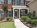 Inviting front porch with brick accents, lush landscaping, and a walkway leading to the entrance at 9700 Ravenscroft Nw Ln, Concord, NC 28027
