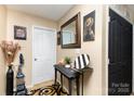 Inviting foyer featuring a decorative mirror, console table, artwork, neutral wall color, and a patterned rug at 9718 Eagle Feathers Dr, Charlotte, NC 28214