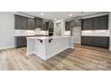 Spacious kitchen with a large island, dark cabinetry, stainless appliances, and hardwood flooring at 9952 Manor Vista Trl, Kannapolis, NC 28027