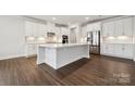 Bright kitchen features a large island, white cabinets, stainless steel appliances, and hardwood floors at 9952 Manor Vista Trl, Kannapolis, NC 28027