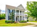 Charming two-story home featuring a covered porch, black shutters, and lush landscaping at 1044 Shiloh Bend Trl, Fort Mill, SC 29715