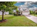 Landscaped front yard with a charming two-story home featuring stone accents and a two-car garage at 130 Bay Laurel Dr, Mooresville, NC 28115