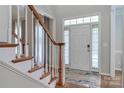 Bright foyer featuring a staircase with wooden handrail and a view of the front door at 212 Forest Walk Way, Mooresville, NC 28115
