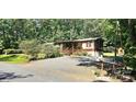 View of the house featuring a gravel driveway, well-kept landscaping, and wooded surroundings at 217 Eighth Ave, New London, NC 28127