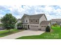 Charming two-story home features a three-car garage, manicured lawn, and inviting curb appeal at 3211 Gilroy Dr, Fort Mill, SC 29707