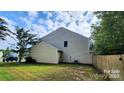 Backyard featuring green grass, a wooden privacy fence, and mature trees creating a serene outdoor space at 4009 Egrets Nest Ct, Mount Holly, NC 28120