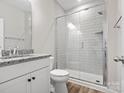 Modern bathroom with sleek white tiles, glass-enclosed shower, and granite countertop vanity at 6012 Millbridge Pkwy, Waxhaw, NC 28173