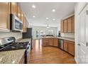 Well-equipped kitchen with stainless steel appliances, granite countertops, wood cabinets, and hardwood flooring at 6315 Prosperity Church Rd, Charlotte, NC 28269